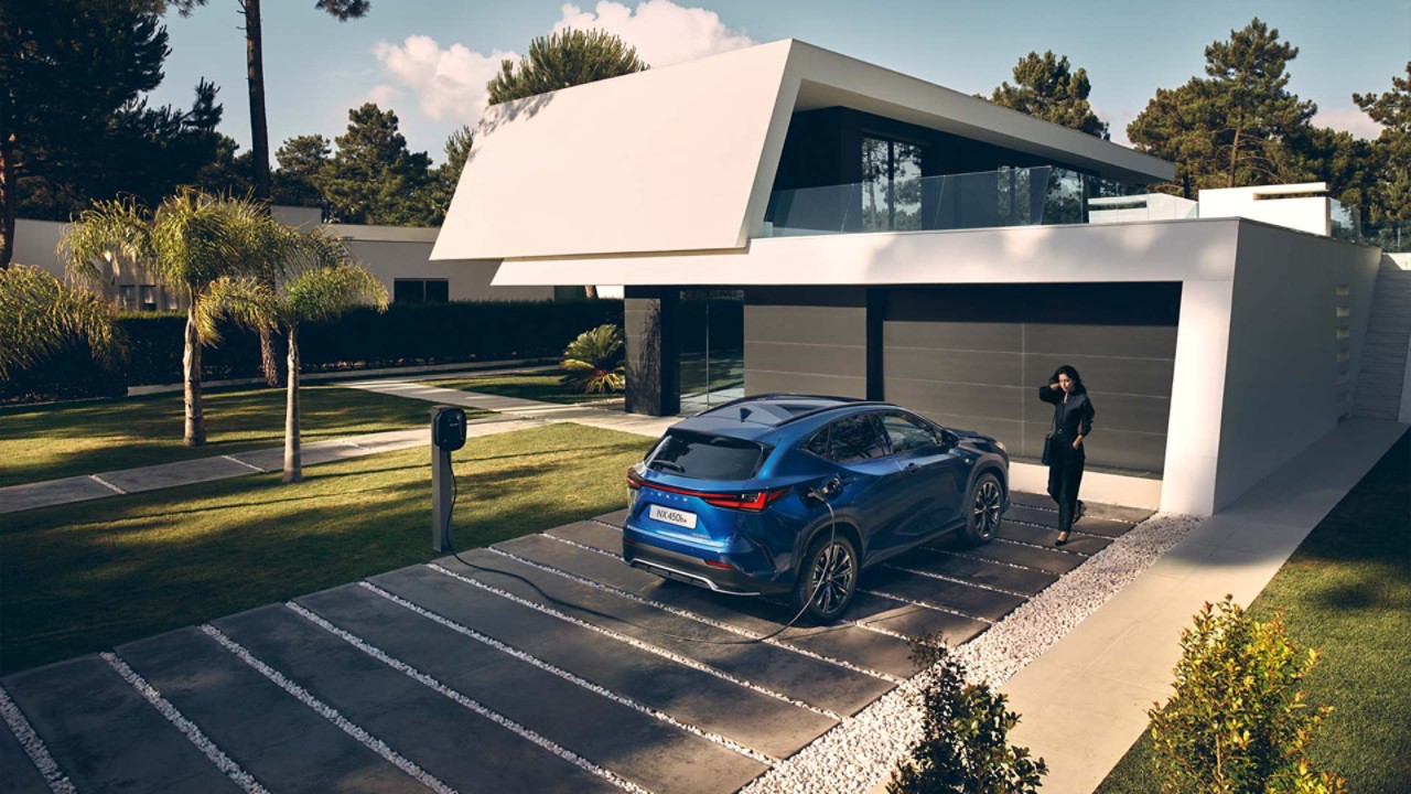 A Lexus NX plugged into a charging tower outside a home